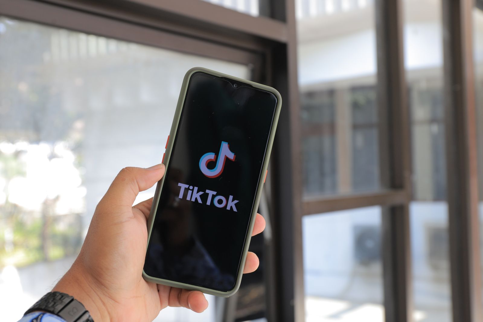 Main tenant un smartphone affichant l'application TikTok