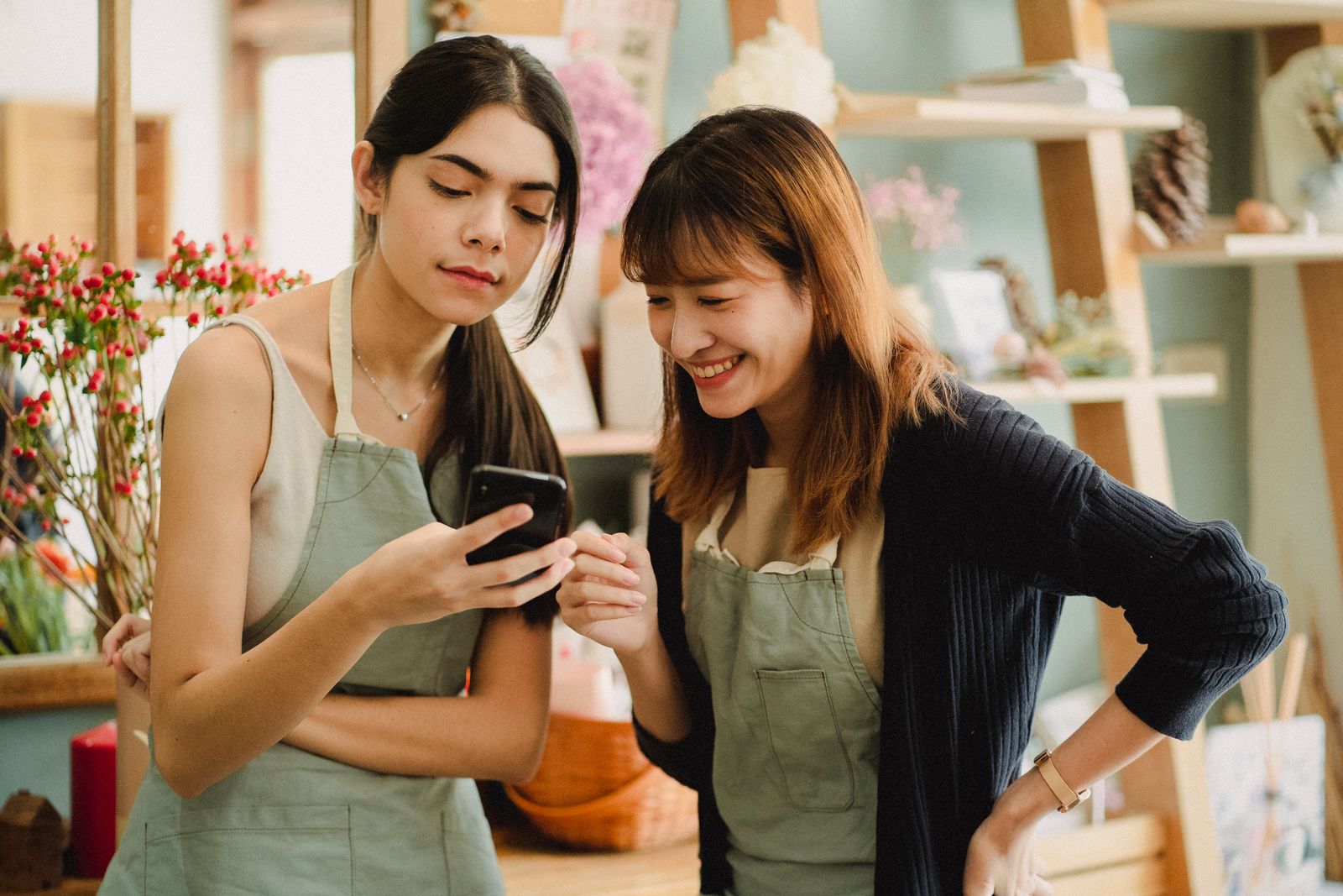 Deux collaboratrices d'une boutique de fleurs consultant leur smartphone pour la communication digitale de leur TPE