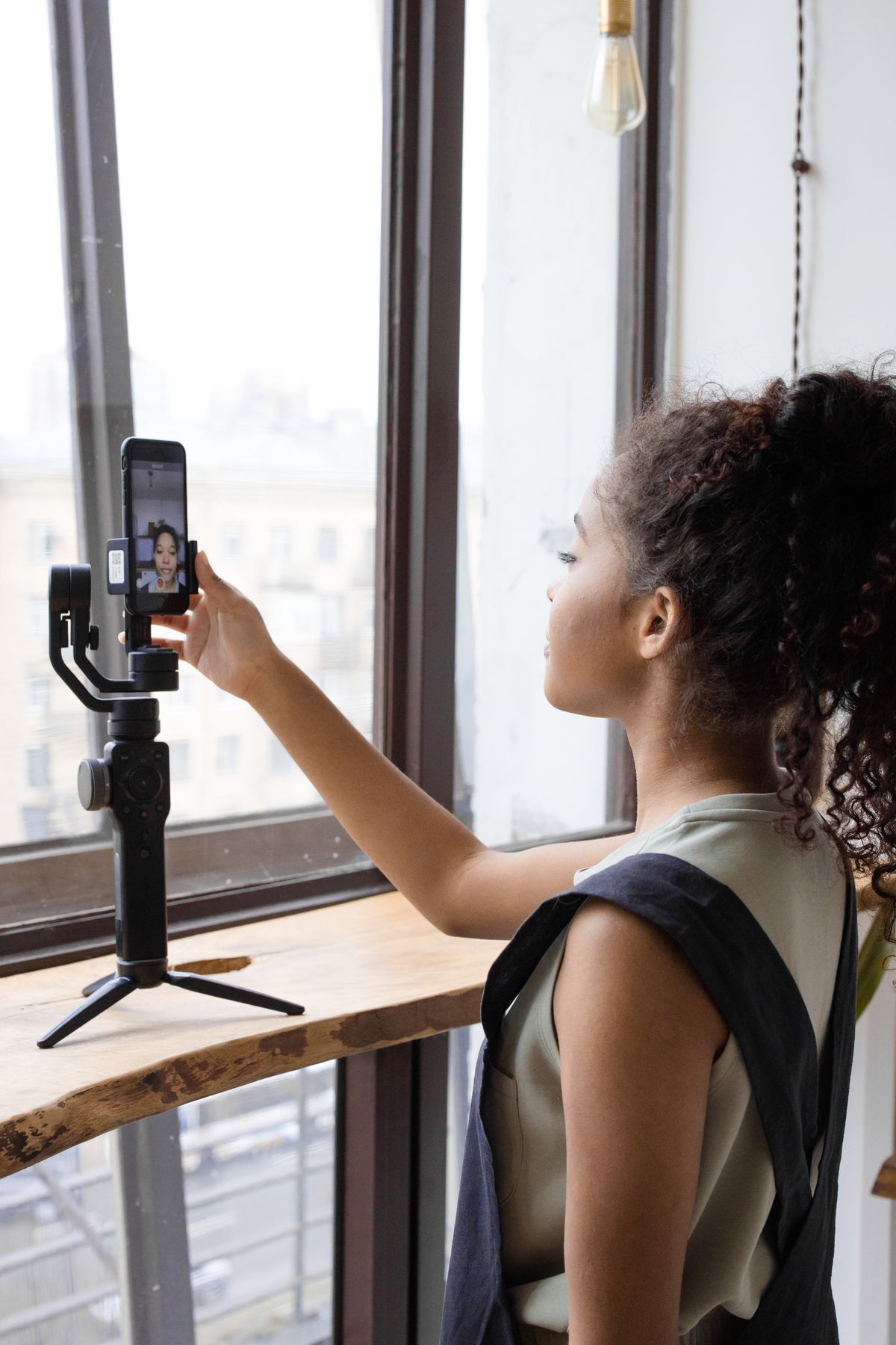 Jeune femme réglant son smartphone sur stabilisateur pour créer du contenu, une compétence clé du community management
