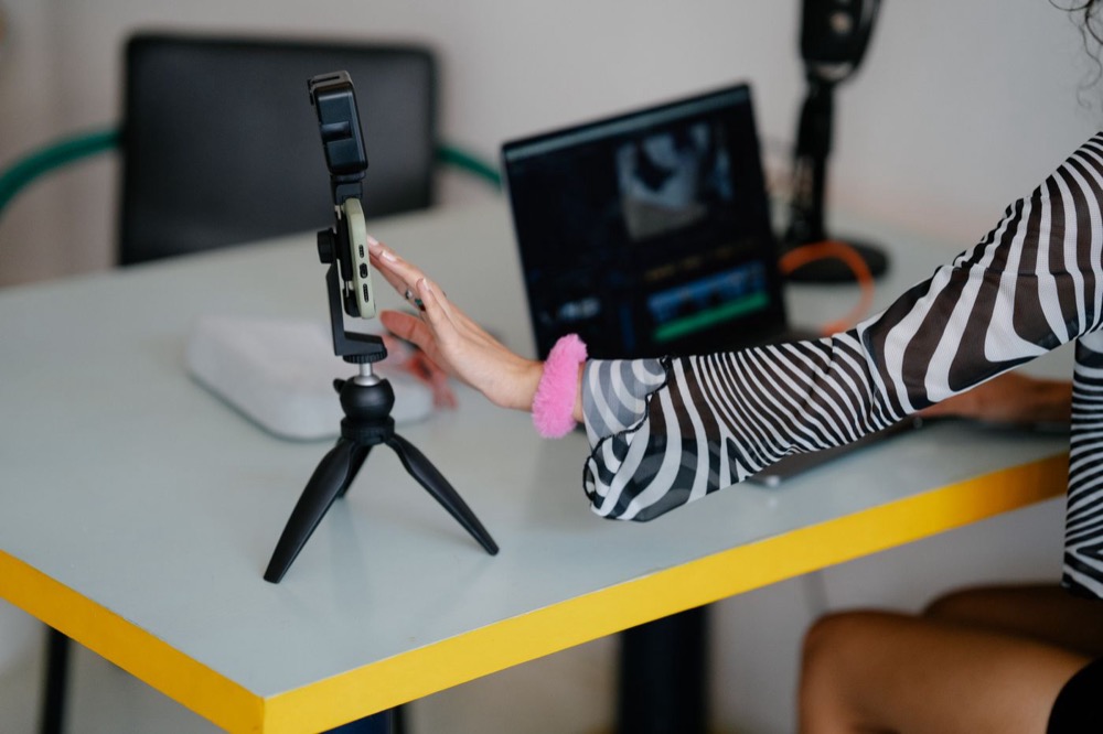 Smartphone sur trépied devant un ordinateur de montage vidéo, comme l’assistant IA d’Edits pour créer ses vidéos