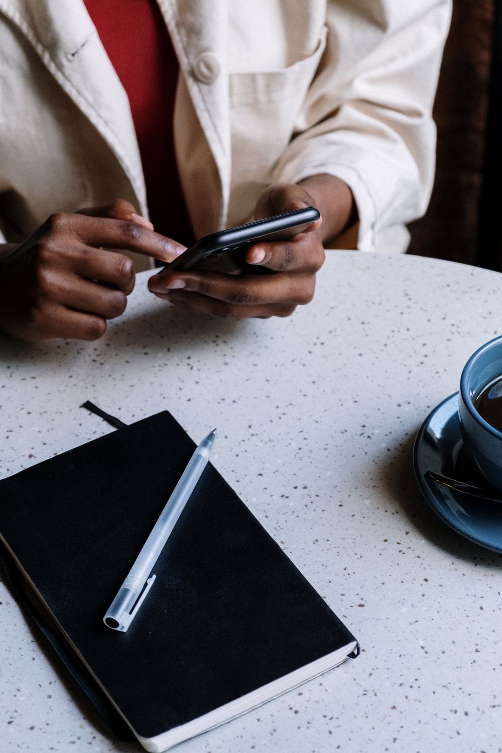 Personne écrivant un message privé sur son smartphone à une table de café, comme une conversation avec Meta AI sur Threads